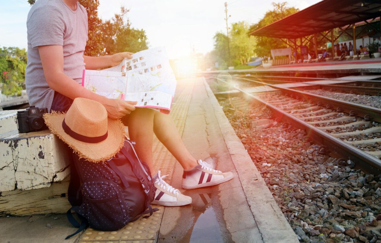 Man sitting next to a black backpack at a railway station