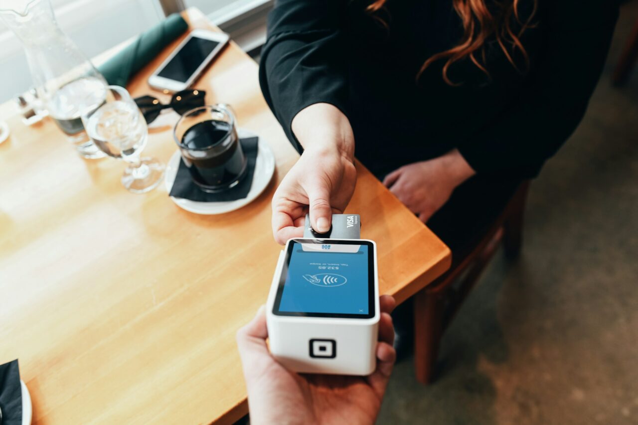 Woman paying with visa credit card at a payment terminal at a cafe