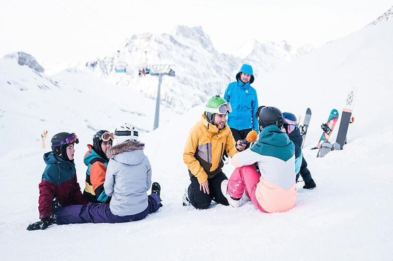 Adults and kids sitting on a ski slope