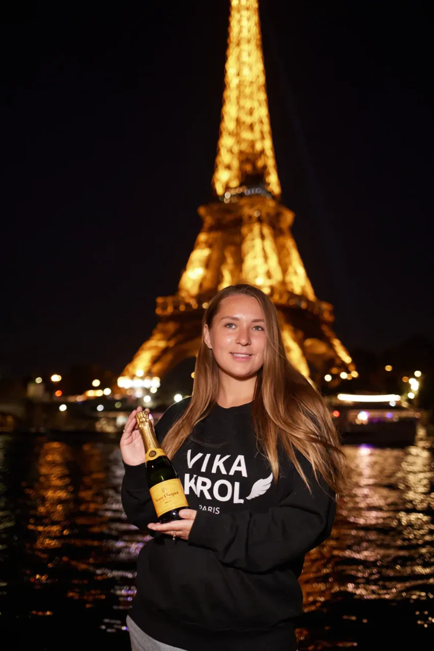 Woman holding champagne in front of the Eiffel Tower 