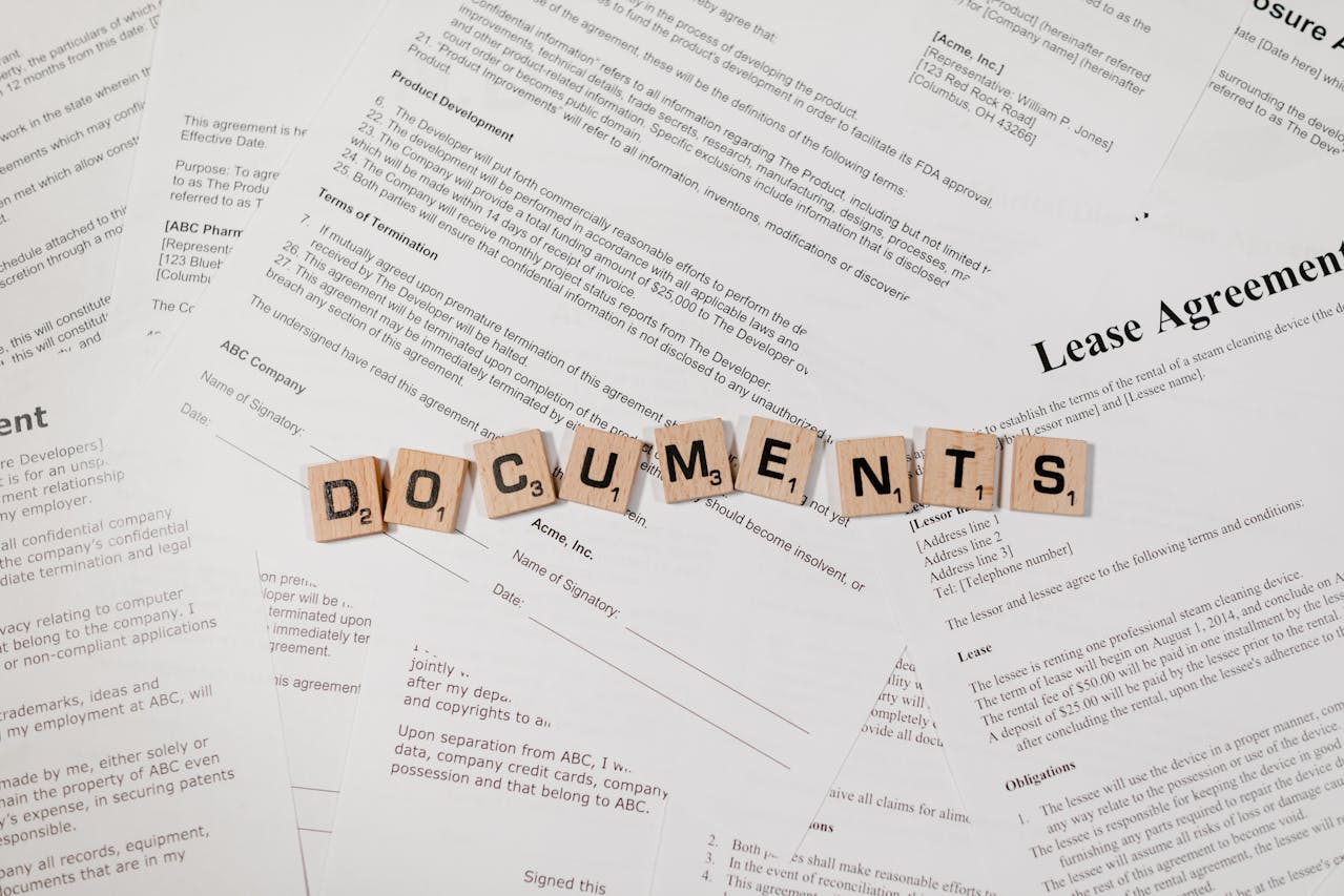 Top view of Scrabble tiles spelling 'DOCUMENTS' on various contracts and agreements.