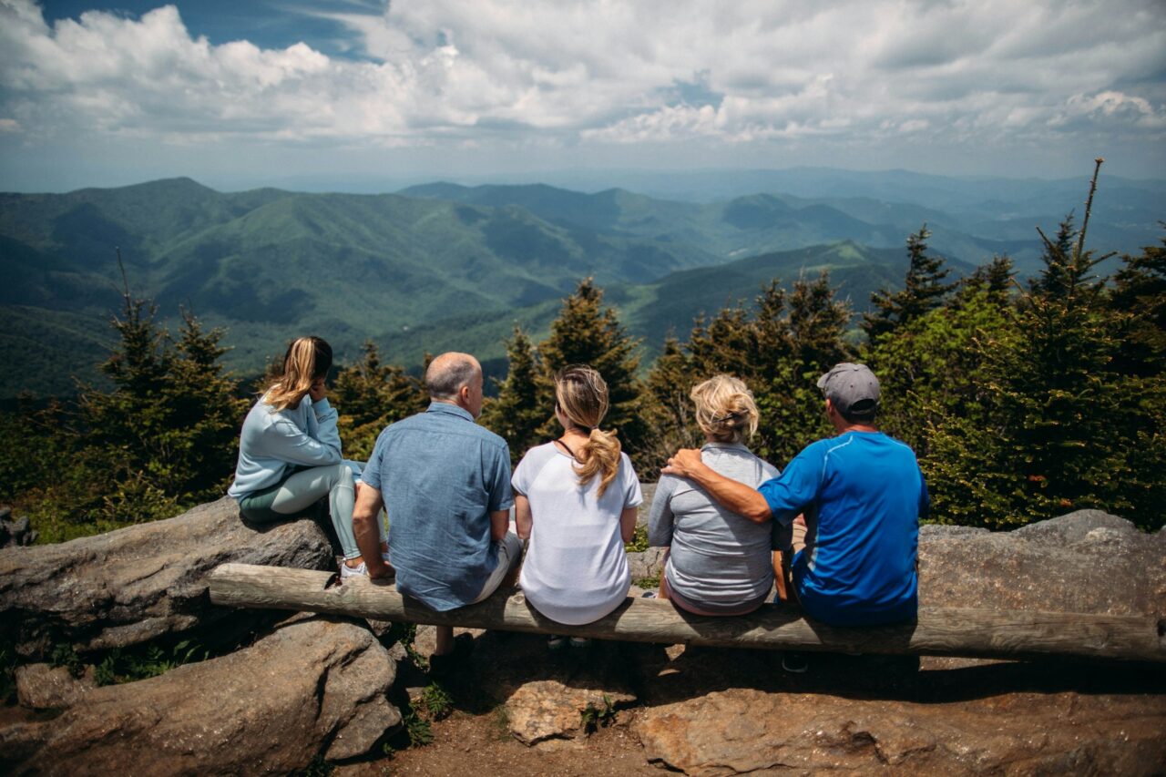 Family sitting on a log overlooking mountains