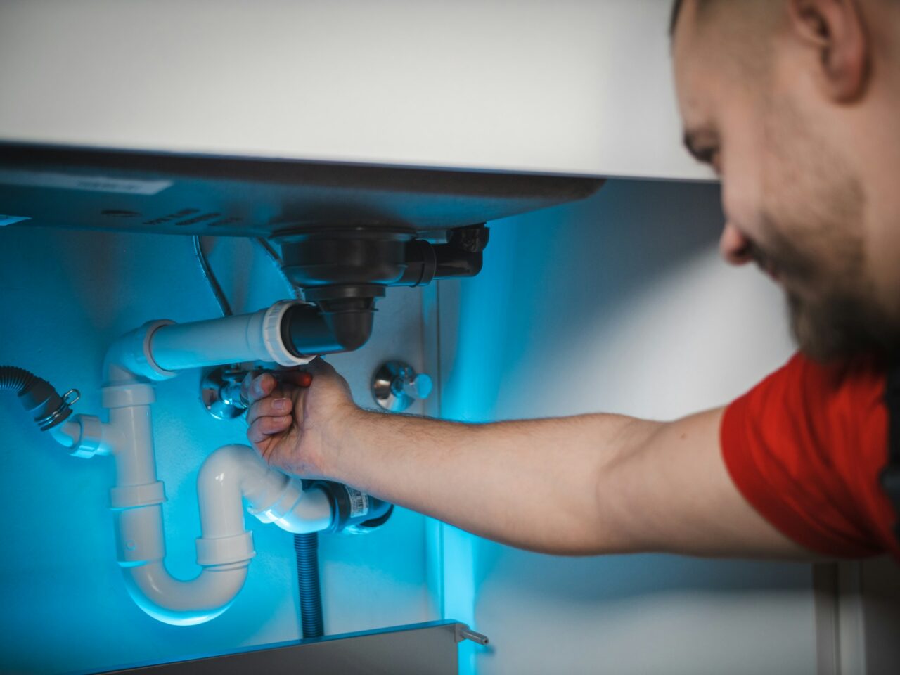 Man inspecting plumbing under sink