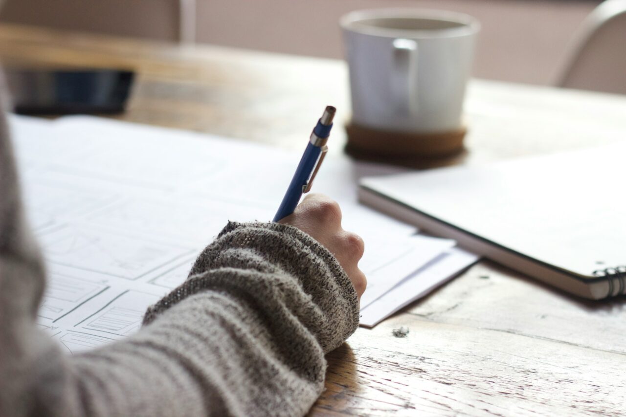 Close up of person's arm holding a pen at a desk