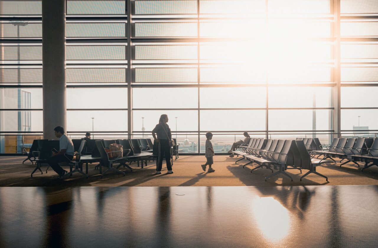 Travelers in a sunlit airport terminal.
