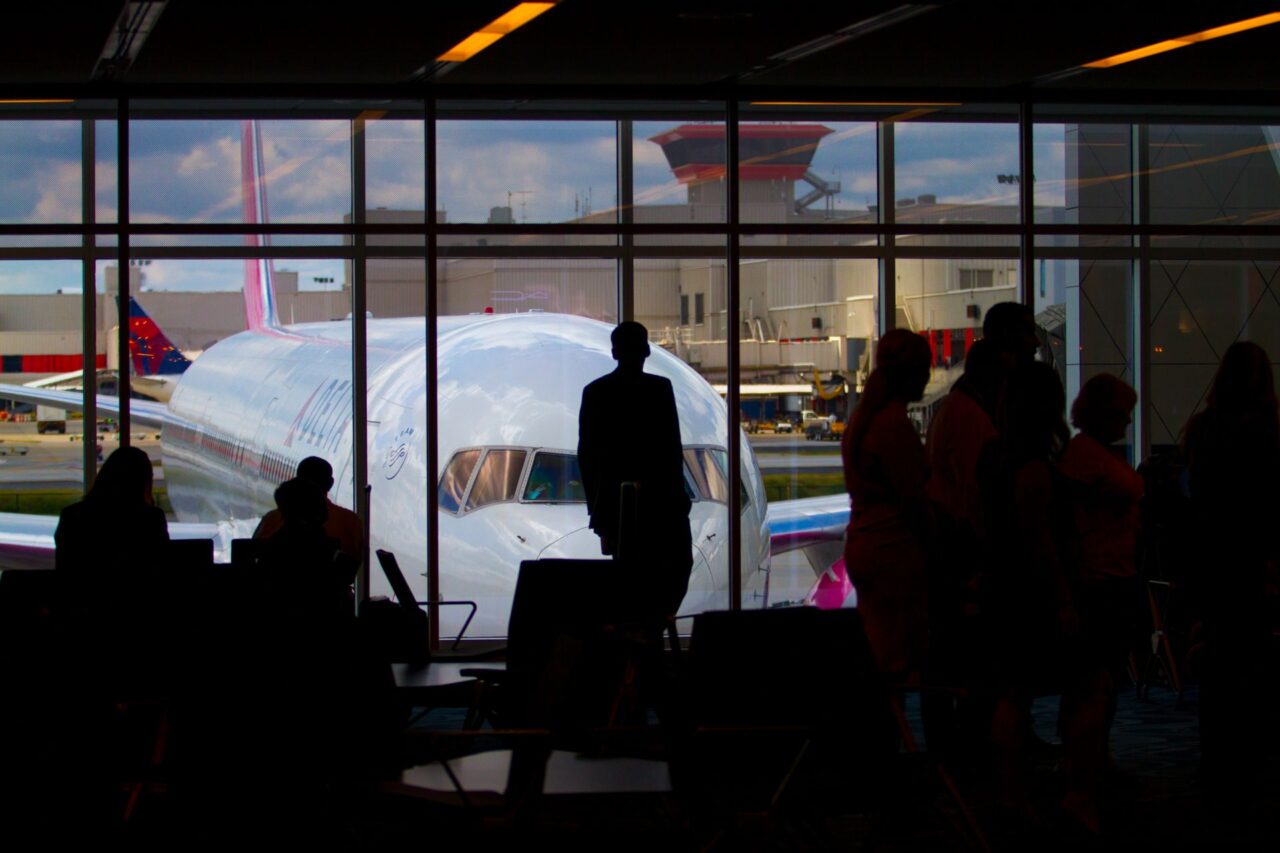 Silhouettes of travelers waiting at an airport terminal.