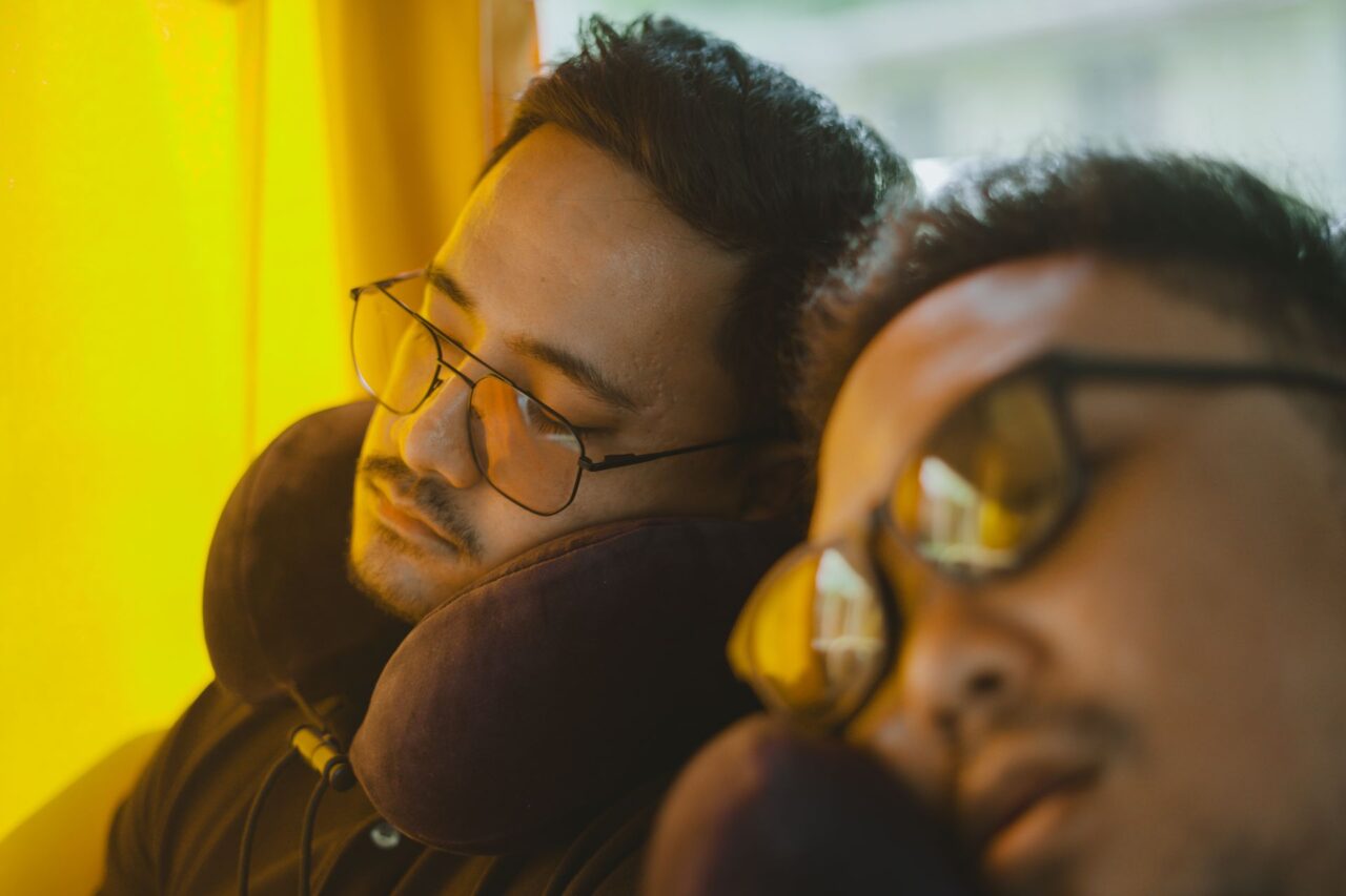 Two travelers wearing eyeglasses sleeping.