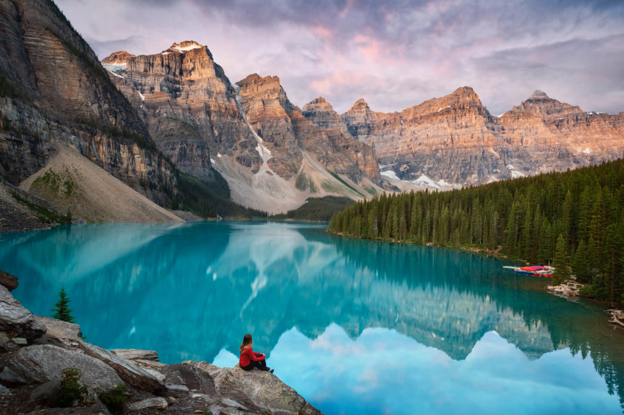 Woman sitting next to a lake with mountains in Canada