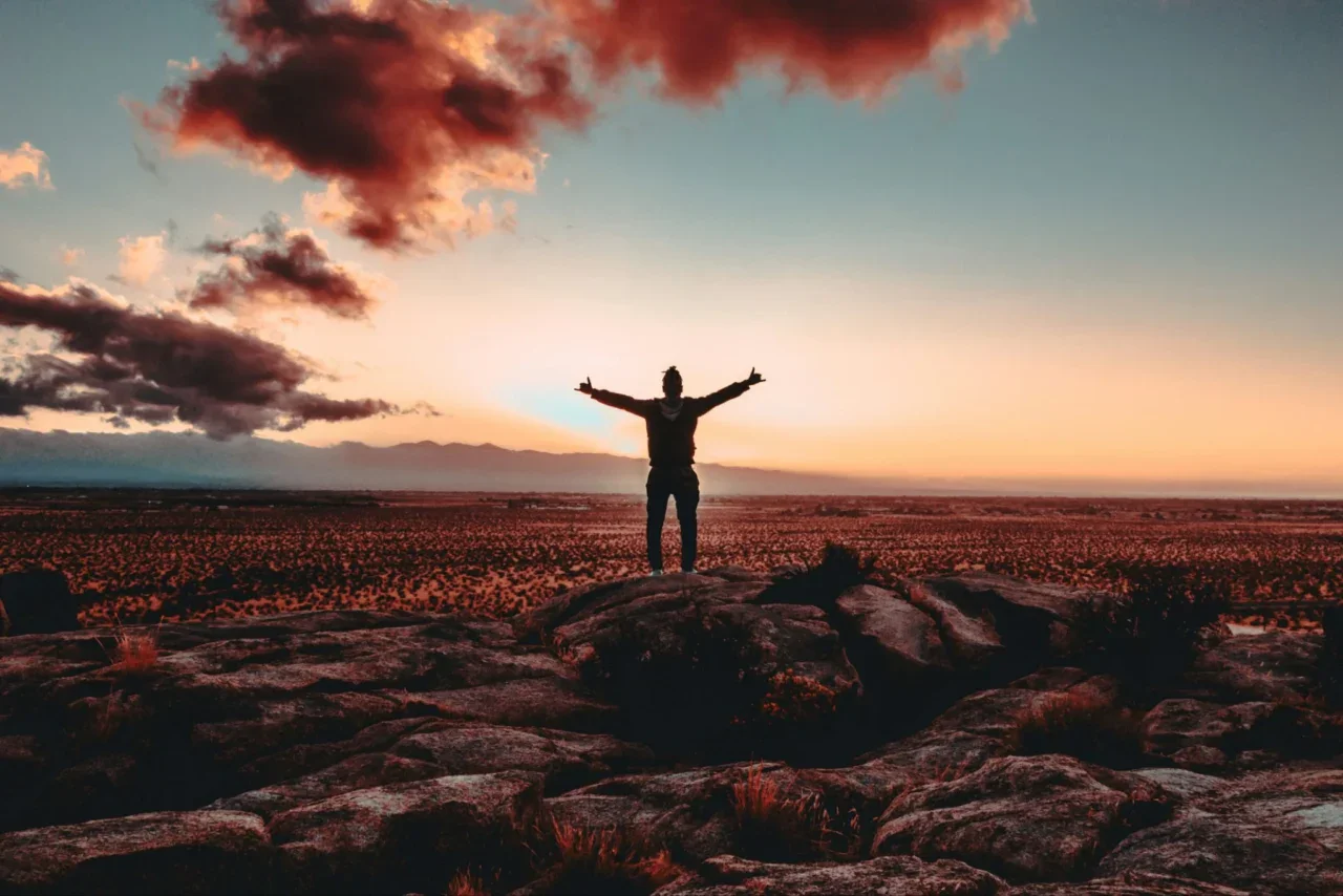 Silhouette of a person with arms up at sunset