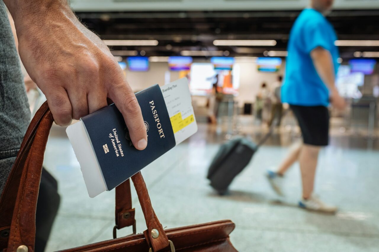 Close up of person's hand with passport and bag at the airport