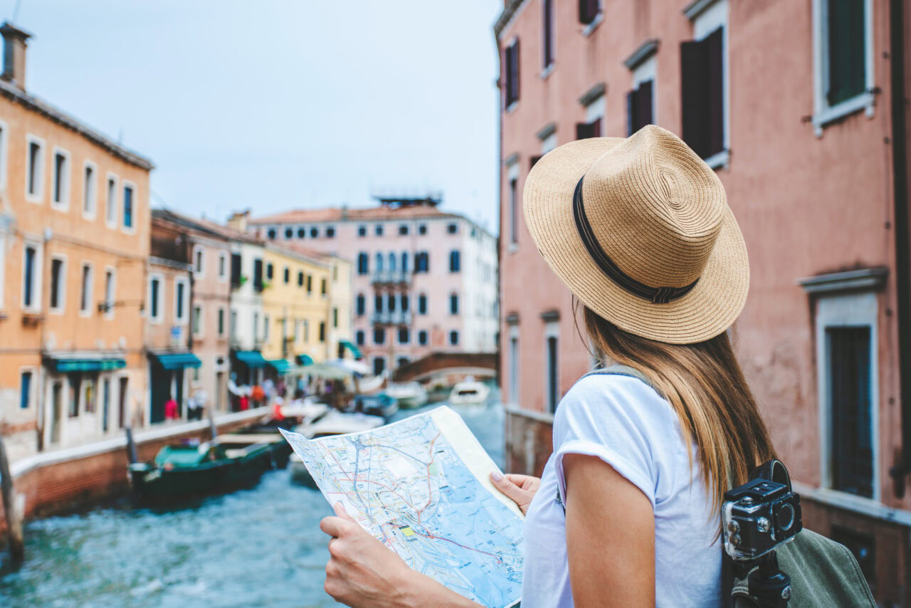 Girl with a map looking out from a bridge in Venice