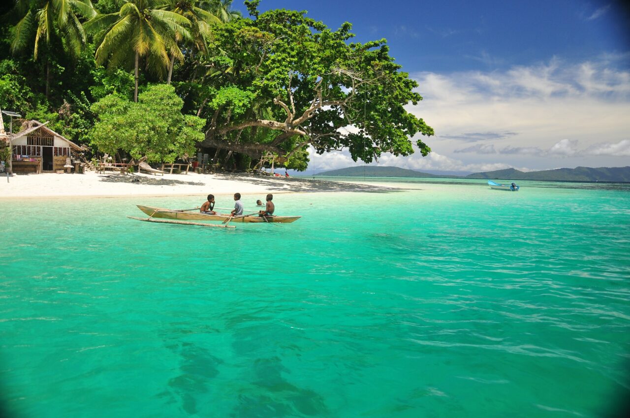 Kids in a boat next to a beach in Raja Amat