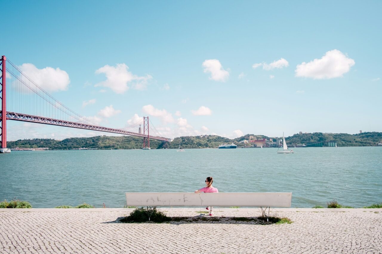 Person sitting on a bench next to the water in Lisbon