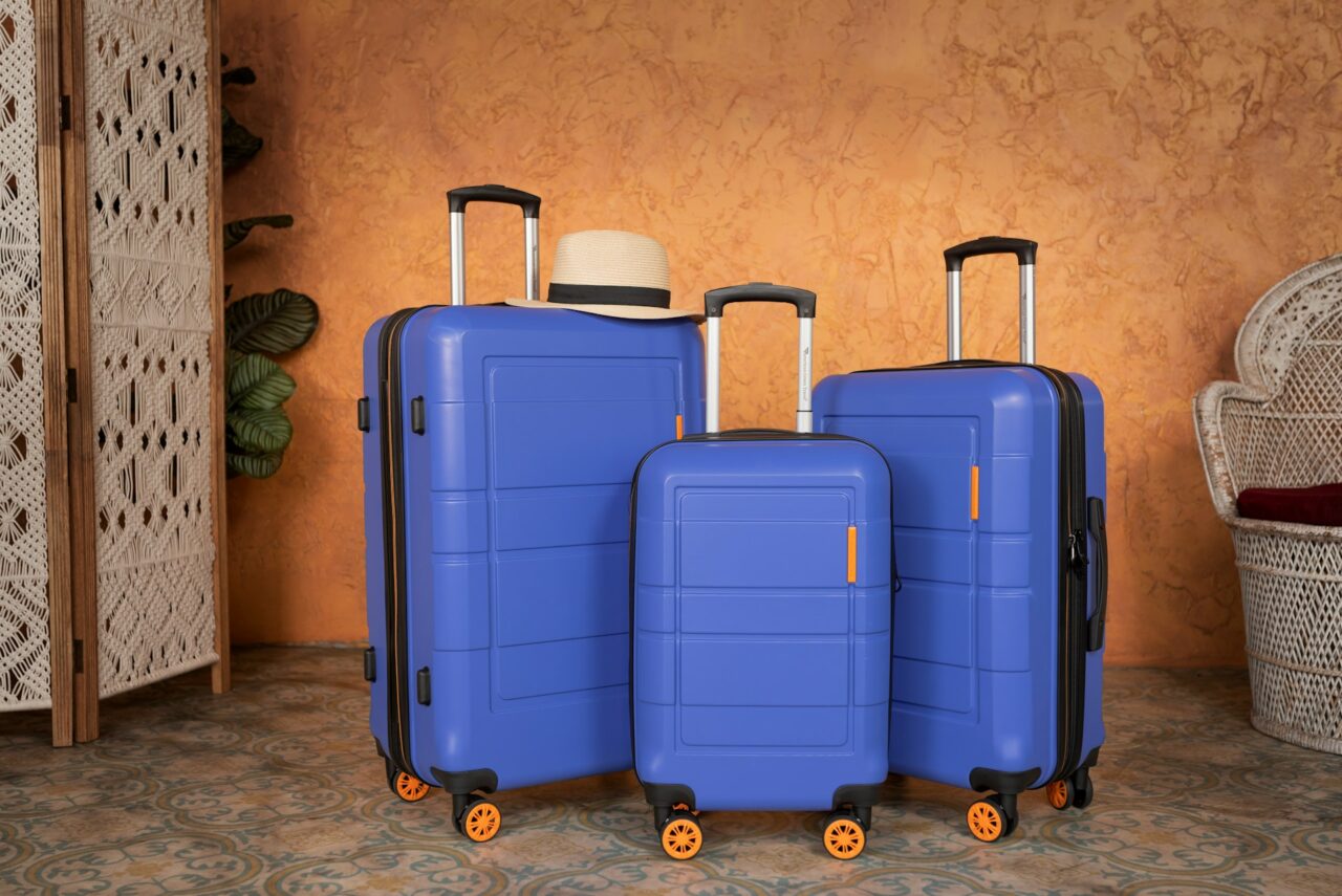 Three blue suitcases next to an orange wall